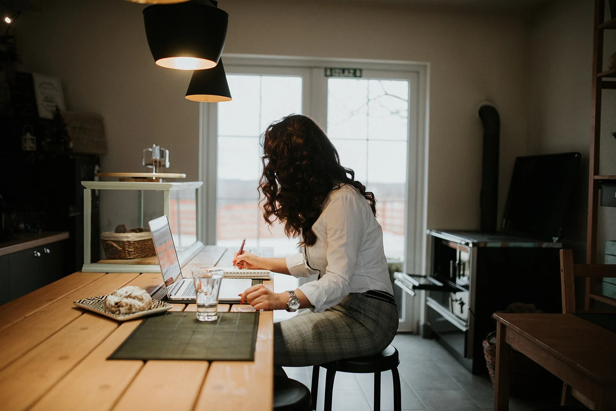 Donna al lavoro con computer portatile e appunti a un tavolo
